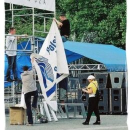 Zdjęcie przedstawia przygotowania do wydarzenia. Mężczyźni wieszają banner Polskiego Radia Szczecin.